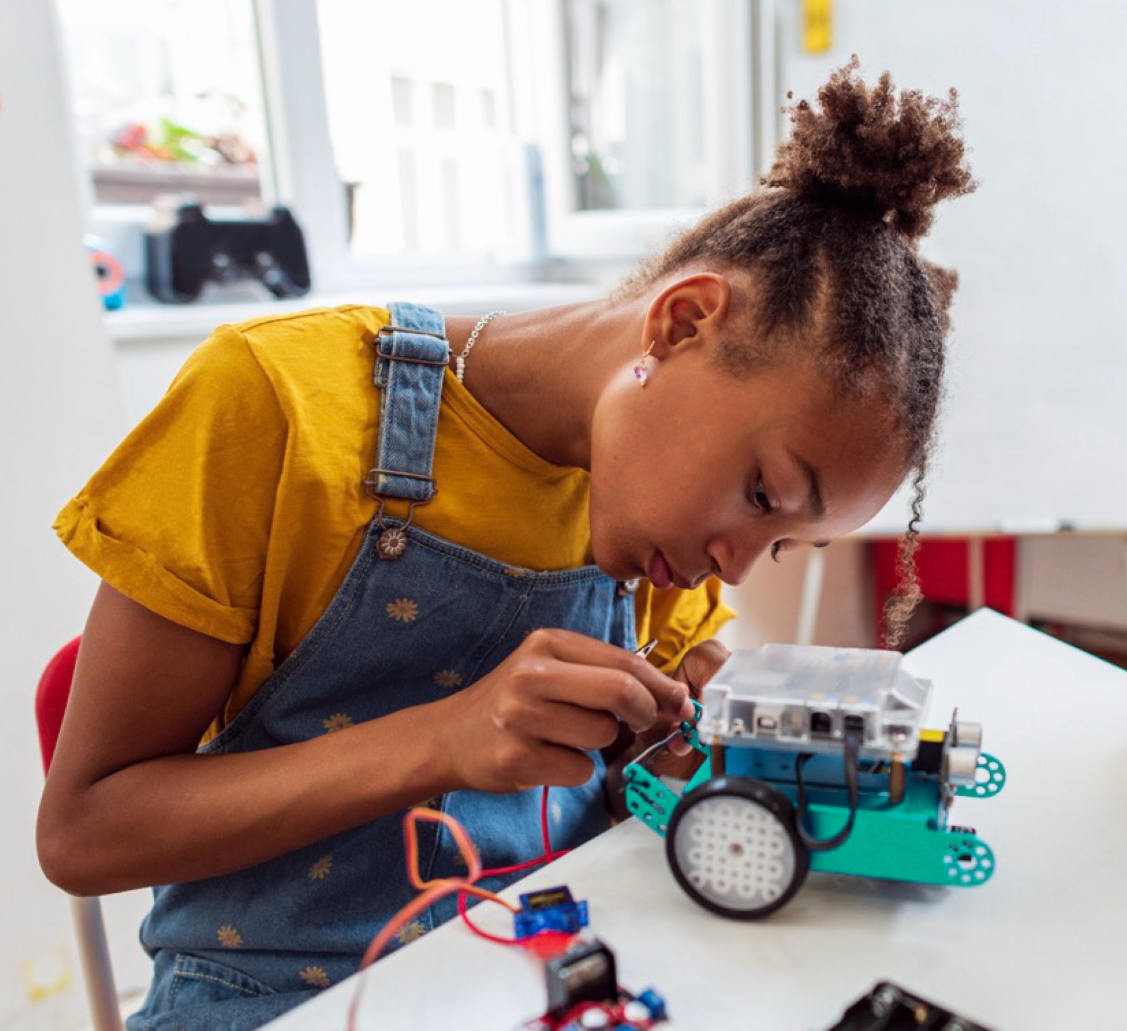 A student assembling a small wheeled robot